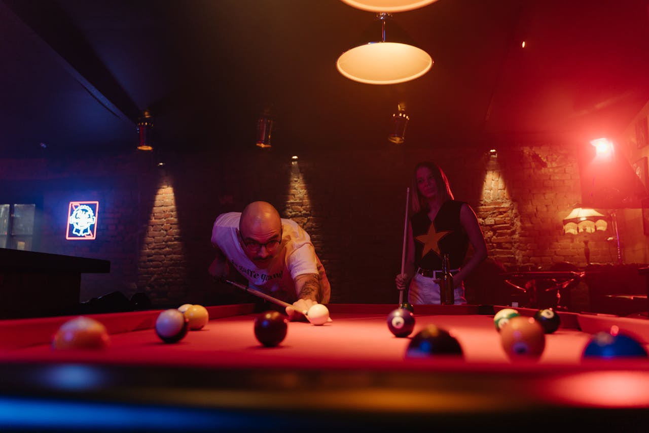 Two people enjoying a thrilling game of pool at a lively bar.