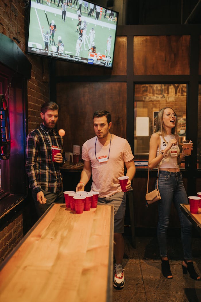 A lively group of young adults playing beer pong in a Denver bar with a fun and energetic atmosphere.